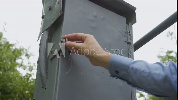 man opens a padlock, man opens a padlock on an old electrical panel with a key