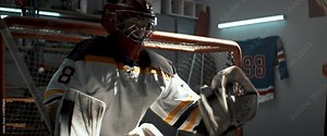 Kid boy goalie practicing hockey shots inside a covered garage. Hockey practice in summer. Shot with 2x anamorphic lens