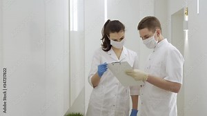 A tired masked doctor walks down the white corridor of the hospital in quarantine