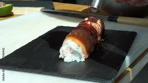 Sushi master prepares sushi in modern style. Chef is blowing fire by blowtorch on salmon Sushi. Fusion cuisine, caramelized salmon on sushi