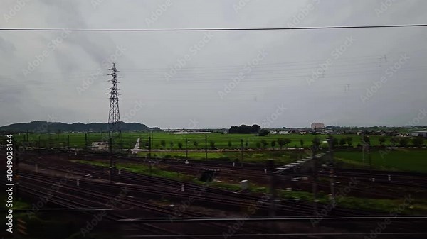 POV from a Shinkansen bullet train window while it drives in the countryside of Japan on stormy day