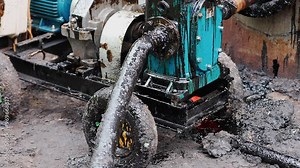 Oil pumping machine working and vibrating pumping oil from tank. Oil flows through hose