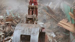 old house being excavator demolished by a large backhoe wooden planks and rubble and the ruins