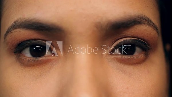 A young woman opens her eyes in slow motion - looking at camera long eyelashes eye care eye yoga. Indian woman with black eyes opens her eyes - macro zoom shot close-up of woman’s face gorgeou...