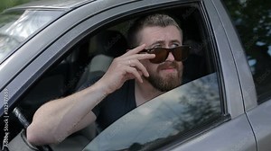 Driver stops and touching glasses while looking throught the car window