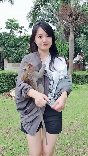 Young Woman Cuddling Monkey in a Scenic Garden