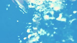 Girl swimming underwater in pool with bubbles rising to water surface