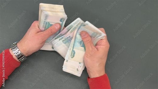 Man counts a bundle of bills for one thousand Russian rubles at the workplace. Man counts paper, 1000 rubles bills. Russian cash money in male hand. A man holds a wad of money in his hands. Money.