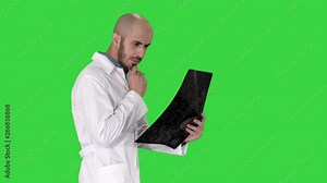 Young male physician reading and reviewing a MRI brain scan while walking on a Green Screen, Chroma Key.