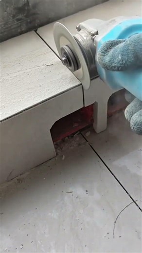 using a power angle grinder with a circular blade to cut precise lines in grey floor tiles on site