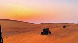 Silhouette dune buggy explores the abandoned terrain of the sweltering desert during a sunset sandstorm. High quality 4k footage