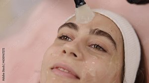 Conductive gel, Client care, Treatment preparation. Before initiating RF lifting treatment, cosmetologist spreads conductive gel onto patient's skin using knuckle.