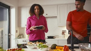 Couple in kitchen wearing fitness clothing making batch of healthy meals in advance for fridge- shot in slow motion
