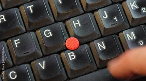 Removing the red pointing stick on a laptop computer keyboard, macro detail extreme closeup shot from above, nobody, no people. Mouse input emulation on notebooks laptops concept. Mouse track point