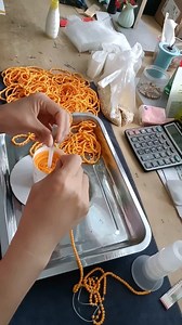 Stringing small artificial pearls onto a thread with precision using a needle, rotating a cylinder filled with pearls to guide each one onto the needle by hand. A delicate and intricate process, each pearl aligns perfectly as the worker's steady hand threads them in place. This traditional craft blends patience and skill, creating beautiful pearl jewelry or decorations one by one. A mesmerizing and satisfying process to watch! | Asian Technology