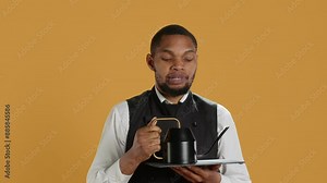 Restaurant staff serving clients with tea before their dinner order, bringing the teapot at the table. Waiter dressed in apron serves customers for satisfaction, service oriented industry. Camera A.