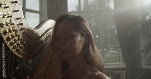 Young female harpist playing harp in dark studio Stock Video