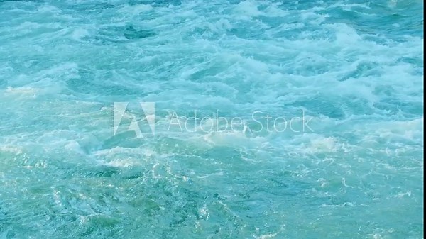 Rapidly seething stream of water. Big powerful river waves. White foam and water ripple. Foaming and splashing in the ocean. Strong flow of a mountain river. Blue clear water