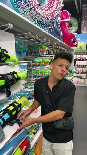 Young Man Explores Colorful Water Guns in a Store