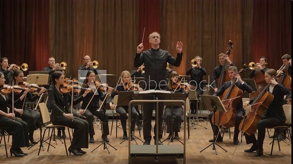 Majestic symphony orchestra performing classical music on a beautiful stage, with the conductor passionately directing the talented string and brass musicians during a live concert performance