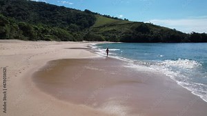 Brazilian woman in bikini on a deserted beach in Ubatuba, São Paulo, Brazil. Playing in the sea water Atlantic forest, yellow sand and clear sea water. Figueira beach paradise.