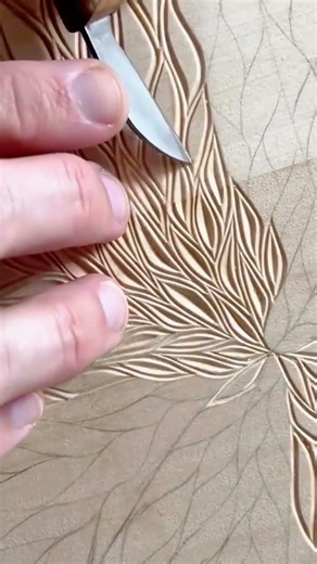 carving detailed leaf patterns on a wooden surface with a sharp metal blade for artistic decoration