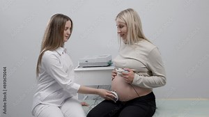Doctor prepares a pregnant woman for checking fetal heartbeat by fetal monitoring Stock Video