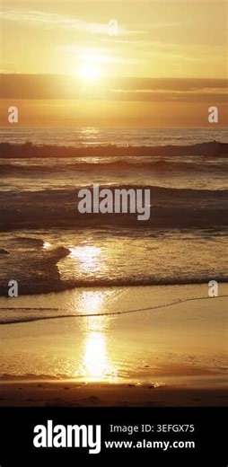 Cinematic 4K slow motion footage (150 fps) of gentle ocean waves rolling onto the beach during a majestic golden sunset. The warm evening light illuminates the water and sky, Guincho beach, Portugal Stock Video Footage - Alamy