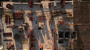 A drone video showcasing a top-down view of a construction site. The image captures the building's foundation, scaffolding, and materials, highlighting the early stages of architectural development