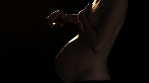 Close up as woman pours oil over her belly. Low key