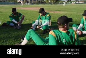 Picking up baseball from grass, diverse male teammates discussing strategy near infield. Athletics, teamwork, sportsmanship, casual, outdoor, vibrant, camaraderie