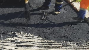 Road street repairing works. Construction workers during asphalting road. Manual labor in construction. Workers are leveling new asphalt on the road