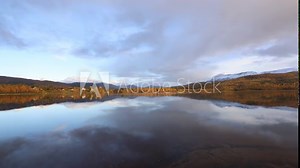 Autumn landscape of Northern Norway, with colorful trees, serene water reflections, and dramatic mountains.
