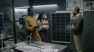 Side full medium footage of diverse engineering team discussing how to enhance photovoltaic cells using solar panel prototype during meeting in office