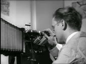 B/W 1940s close up scientist looking into microscope in laboratory /...
