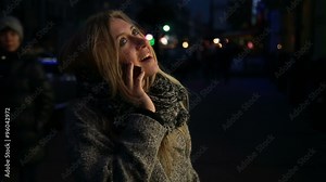 Young beautiful girl talking on a cell phone and smiling on the street at night