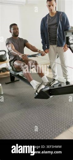 Vertical video: On trainer cue African American male rower paddling in gym for fitness, copy space. Fitness, training, strength, endurance, wellness, motivation, vertical video Stock Video Footage - Alamy