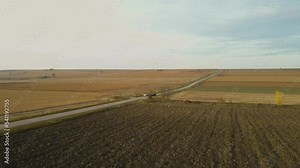 Two cars compete and drive fast on the highway. Race on passenger cars. Plain terrain. Fields and agricultural land. Competition. Adrenaline from speed. View from drone