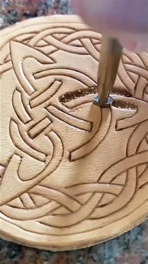stamping intricate celtic knot patterns on a leather surface using a metal tool for leathercrafting
