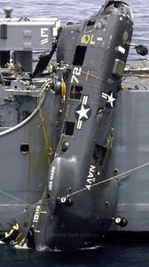 A US Navy UH-46 Sea Knight helicopter, hanging from the side of the destroyer USS FIFE (DD-991) below the helicopter pad, is tied off with support ropes. The helicopter crashed on takeoff due to an engine failure | History Vault Archives