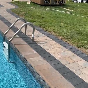 Cambridge Toffee/Onyx pavers with Coal borders for this back yard patio. Added a wall with a couple 24” stainless scuppers and some leds lights. #outdoorliving #landscapeconstruction #cambridgepavers #retainingwall #waterfall #carrylandscaping | Carry Landscaping Design & Masonry