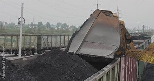 Slow motion loading of an loader into railway wagons. Excavator loading coal into wagons. Loading of coal truck using excavator. Close-up slow-motion loading coals for transportation