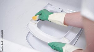 Female hands in rubber gloves washes toilet lid in bathtub with sponge. Washing white modern toilet bowl in bath. . High quality 4k footage