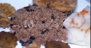 Cuban plate of traditional food, rice and beans boiled yuca, smashed fried bananas and chicken steak rotating on a turning table