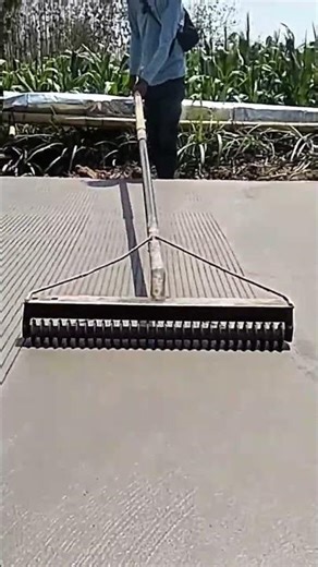 Manual process worker creating neat line texture on wet concrete surface