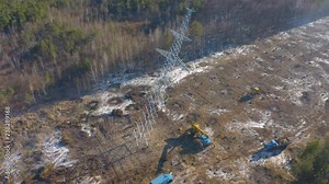 Aerial circling view of the power line pylon installation by steel erector workers in power transmission line right-of-way