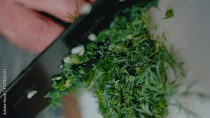 Chopped dill on a knife blade, highlighting the texture and freshness of the herb. Ideal for a stock video clip on culinary arts, ingredient preparation, and healthy cooking.