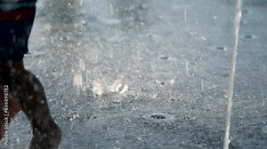 Child feet in splashing water playing at park water jet outdoors