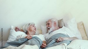 Elderly couple at home. Old woman and man having fun laughing in bed in the morning. Concept about third age and love