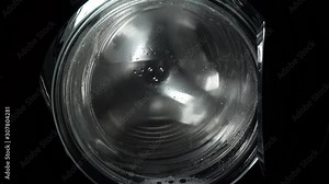 Spin the laundry in the washing machine. Close up view. The washing machine on a black, dark background. Spinning drum. The washing process in the washing machine.